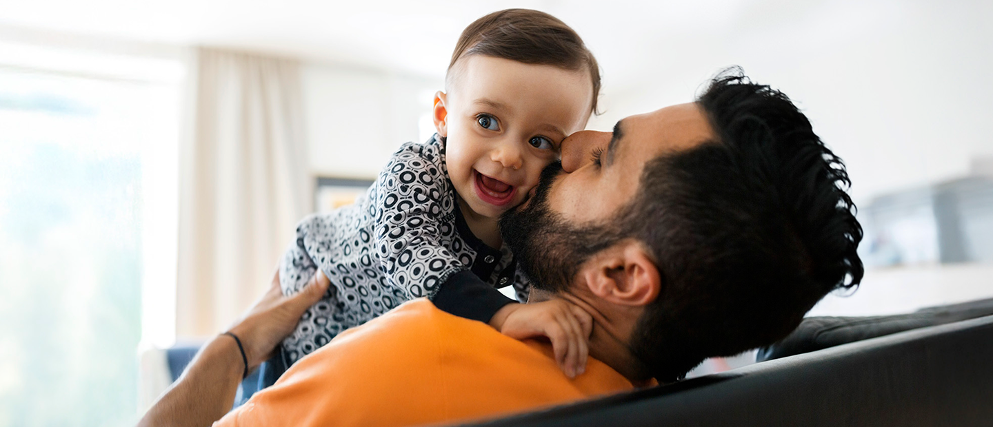 Woman standing in the sunshine outside her home and smiling while tending to her green garden.