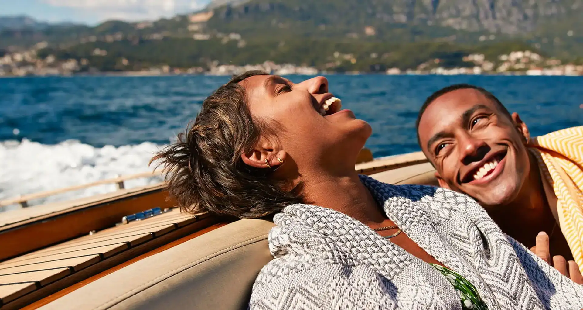 Man and woman relaxed and laughing while enjoying a boat ride in a sunny climate.
