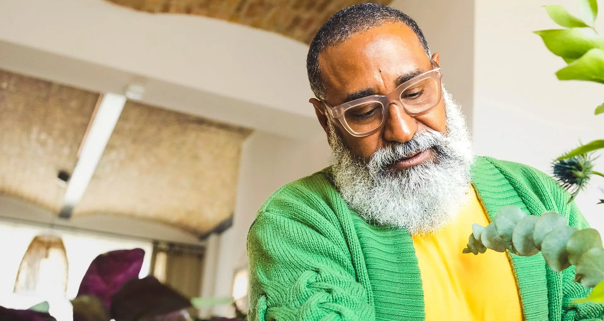 Relaxed gentleman who is mindfully tending to his indoor plants in his home environment.
